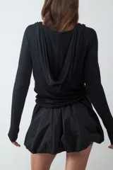 Top de manga larga color negro, con escote drapeado y detalle de tiras finas para anudar en el cuello. Confeccionado en tejido elástico y suave.