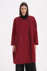 Tapado de textura bouclé en color rojo, con diseño de corte recto, sin cuello y cierre frontal mediante un único botón. Presenta un ribete en contraste de color negro que recorre los bordes de la prenda.