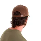 Gorra de béisbol con visera curva, confeccionada en cuero sintético de aspecto desgastado en color marrón. Presenta un pequeño aplique metálico con el logo de la marca en el lateral y cierre ajustable con hebilla metálica en la parte posterior.