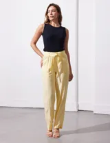 Pantalón de lino color amarillo, de corte recto y tiro alto. Presenta pretina con pasadores, lazo de ajuste en la cintura y bolsillos frontales aplicados.