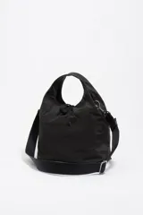 Bolso bandolera de estructura blanda marca Bimba y Lola, confeccionado en nylon con detalles en cuero. Presenta doble asa de mano, correa de tejido regulable y extraíble, cierre de cordón y logo metálico en el frente.