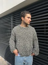 Sweater tejido a mano en lana color gris jaspeado, de calce holgado, con cuello a la base y puños ajustados.