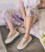 Zapatillas deportivas de lona color rosa pálido con cordones blancos y suela de goma color crema.