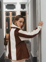 Campera con capucha, de tela tipo peluche a rayas verticales color marrón y blanco, con ribete color beige.