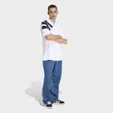 Remera Adidas de estilo retro inspirada en los años 90, con corte holgado y cuello en pico. Presenta un diseño blanco con tres franjas negras diagonales sobre el hombro derecho y logo de la marca bordado en el centro del pecho.