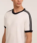 Remera de algodón color celeste con cuello redondo y bordes de mangas en color blanco. Presenta diseño de rayas dobles blancas en los hombros y mangas.