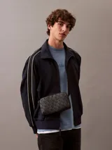 Bandolera Calvin Klein con estampado de monograma CK integral, correa ajustable y cierre con cremallera.
