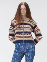Campera de punto estampada de corte holgado, con cierre metálico frontal y cuello de corderito sintético en color tostado. Presenta un diseño de franjas horizontales con patrones geométricos en tonos bordó, mostaza, marrón y beige.