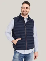 Chaleco acolchado de nailon en color azul marino, con cuello alto, cierre frontal de cremallera con detalles distintivos de la marca y bolsillos laterales con cierre. Presenta el logo de Tommy Hilfiger bordado en el pecho.