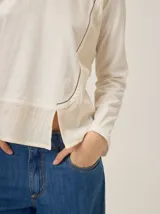 Remera de manga larga en color marrón, confeccionada en una combinación de tejido de punto y tela plana. Presenta un diseño de superposición frontal con costura decorativa en contraste y un panel inferior de textura diferenciada.
