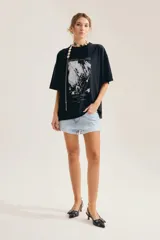 Remera oversize de algodón color blanco, con cuello redondo, mangas cortas y estampa gráfica frontal en blanco y negro con diseño vintage.