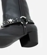 Bota corta de cuero sintético color negro, estilo western, con puntera fina, taco cuadrado y detalles de tachas plateadas.