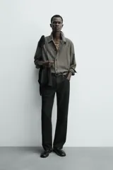 Sobrecamisa de corte cropped confeccionada en tejido ligero con algodón, con estampado de cuadros pequeños en tonos oscuros. Presenta cuello solapa, cierre frontal de botones, manga larga con puño abotonado y bajo con elástico en la espalda.