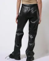 Pantalón de cuero sintético negro, de corte ajustado y acampanado, con cordones cruzados en los laterales.