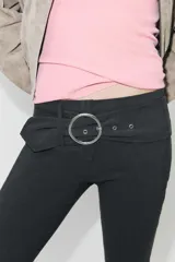 Pantalón capri de tiro medio confeccionado en tejido elástico, con cintura elástica y detalle de cinturón integrado con hebilla metálica circular. Presenta aberturas en el bajo.