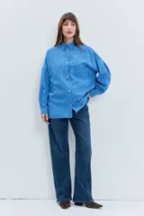 Camisa de corte oversize con estampado de rayas verticales, cuello clásico, cierre frontal con botones y mangas largas con volumen.