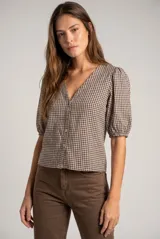 Blusa de algodón con estampado de cuadros vichy en tonos negro y blanco. Presenta escote en V, cierre frontal con botones y mangas cortas abullonadas con terminación elástica.