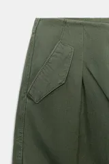 Pantalón cargo de tiro medio con pinzas delanteras, bolsillos laterales de plastrón y cierre frontal con cremallera y botón. Presenta una pernera holgada que se estrecha ligeramente hacia el bajo.