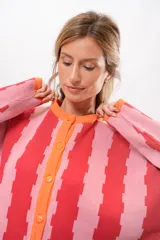 Saco de tejido de punto con rayas verticales rosas y rojas, cuello redondo y botones naranjas.