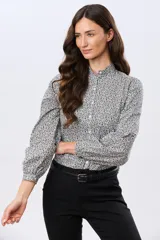 Camisa de algodón celeste con estampado floral pequeño, cuello mao, mangas largas con puños fruncidos y cierre frontal de botones.