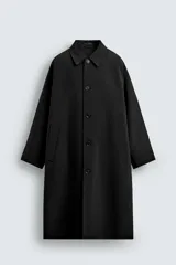 Trench de corte oversized confeccionado en tejido compacto con mezcla de lana. Presenta cuello solapa, cierre frontal con botonadura, mangas largas y bolsillos de vivo en la cadera.