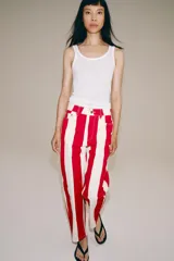 Jeans de tiro medio y corte tapered, con diseño de rayas verticales a contraste en color rojo y blanco. Cuenta con trabillas en la cintura, cinco bolsillos y cierre frontal con cremallera y botón metálico.