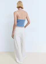 Top de punto fino sin mangas, con diseño entallado, tirantes finos y cuello escotado. Presenta un detalle de borde en contraste en el escote y el ruedo.