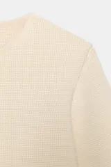 Chaqueta corta de punto color azul marino, de cuello redondo, manga por debajo del codo y cierre frontal con botones forrados al tono.