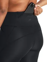 Calza deportiva de tiro alto Under Armour, color negro, con perforaciones láser en la parte inferior de las piernas para mayor ventilación. Cuenta con bolsillos laterales y bolsillo trasero expandible, diseño sin costuras internas y detalles reflectantes.