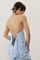 Top halter celeste con diseño asimétrico de corte más largo en la parte trasera, cuello alto y sutil estampado floral.