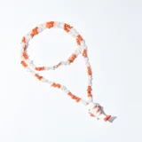 Collar con cuentas de piedra blanca y naranja, con dije de pez blanco con detalles en rojo.