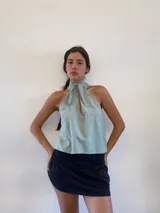 Blusa tipo musculosa de color celeste, con diseño de cuello halter que se ata con un moño frontal. Presenta un corte holgado y versátil.