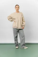 Buzo oversize de algodón frizado color beige, con cuello redondo, puños y cintura tejidos. Presenta un bordado tono sobre tono de Garfield en el frente.