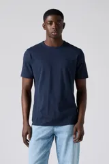 Remera de algodón de corte estándar con cuello redondo y manga corta. Presenta un diseño liso en color azul marino con un pequeño logo bordado en el pecho.
