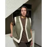 Chaleco estilo gamulán en color verde militar, con forro interior y bordes de corderito sintético en tono crema. Presenta un diseño sin mangas, ideal para usar sobre prendas de abrigo.