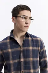 Camisa de manga larga confeccionada en viyela de algodón con diseño de cuadros en tonos azul marino y marrón. Presenta cierre frontal con botones, cuello clásico y un bolsillo en el pecho.