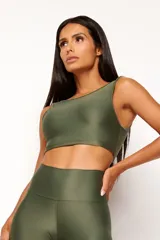 Top deportivo color terracota, de corte crop y manga sisa, con cuello redondo y espalda escotada. Presenta textura acanalada y acabado brillante.