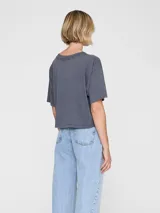 Remera gris oscura de algodón con calce amplio, cuello redondo y estampa tipográfica frontal estilo universitario en tonos claros.