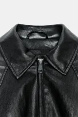 Chaqueta estilo bomber de efecto piel en color verde oliva, con cuello solapa, cierre frontal con cremallera, mangas largas y bajo elástico.