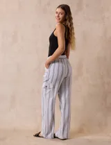 Pantalón cargo de lino a rayas verticales grises y blancas, marca Marissa Olivia. Pretina ancha elastizada con lazo de ajuste, bolsillos inclinados delanteros y bolsillos laterales con botón.