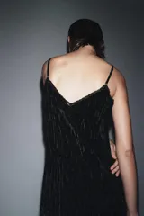 Vestido midi de estilo lencero confeccionado en terciopelo negro, con escote en pico, tirantes finos ajustables y detalles de encaje a tono en el escote y el bajo.