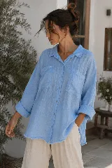Camisa de lino blanca con terminaciones desflecadas, bolsillos frontales en el pecho, mangas largas arremangadas y botones a tono.