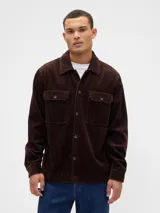 Sobrecamisa de pana color marrón oscuro, con cuello clásico, cierre frontal de botones y dos bolsillos frontales con solapa.