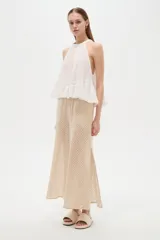 Top blanco de algodón con cuello halter, diseño holgado y detalle de encaje en el borde inferior.
