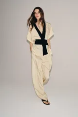 Kimono Zara Woman Collection de manga corta y cuello en V, confeccionado en tejido color crudo con sutiles rayas verticales. Presenta aplicaciones de terciopelo negro a contraste en la solapa y un fajín ancho integrado en la cintura.