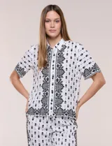 Camisa blanca de manga corta y corte recto, con estampa en contraste de color negro. Presenta cuello camisero clásico y cierre frontal de botones.