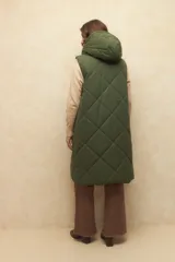 Chaleco largo marrón capitoneado con capucha, cierre frontal y bolsillos laterales. Forro interno de satén con estampado animal print.