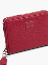 Billetera roja de cuero sintético con cierre perimetral y logo metálico de Tommy Jeans en el frente.