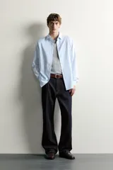 Camisa slim fit de algodón color celeste con sutil patrón de cuadros, cuello clásico y manga larga con puños abotonados.