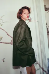 Blazer verde militar de efecto gamuza, con cuello de solapa, manga larga, bolsillos delanteros con solapa, forro interior y cierre frontal con botones.